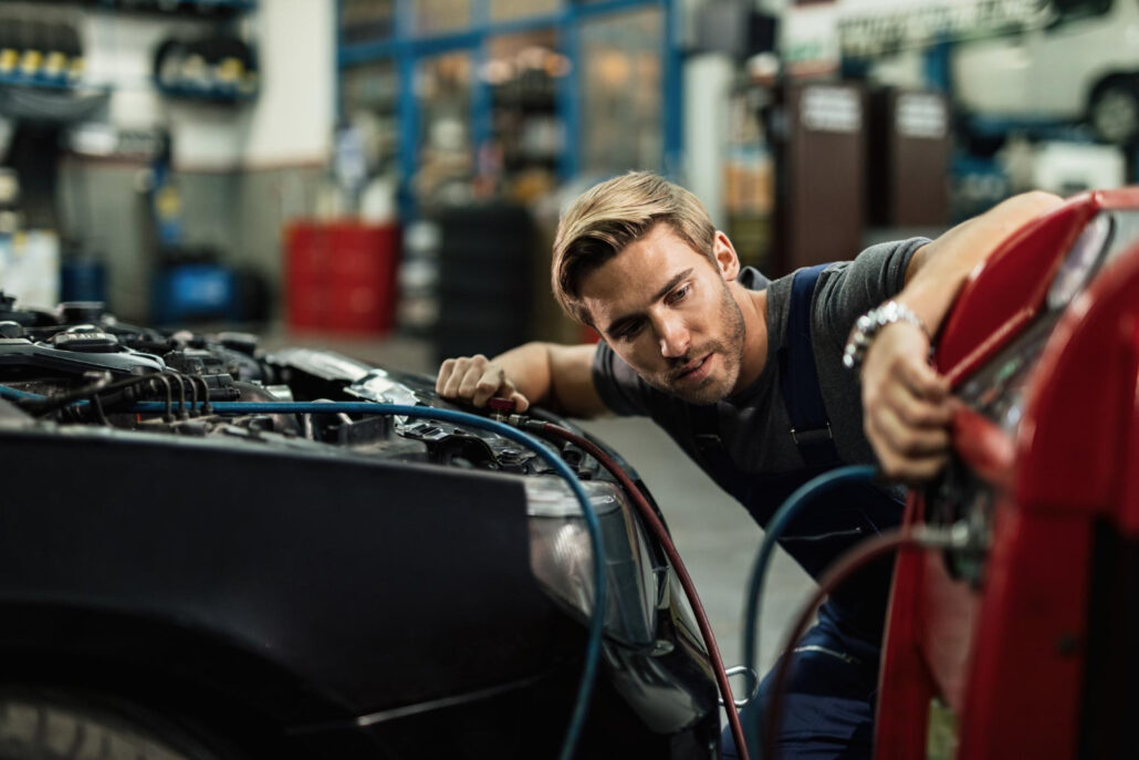 young-auto-mechanic-using-compressor-while-maintaining-ac-unit-car-workshop