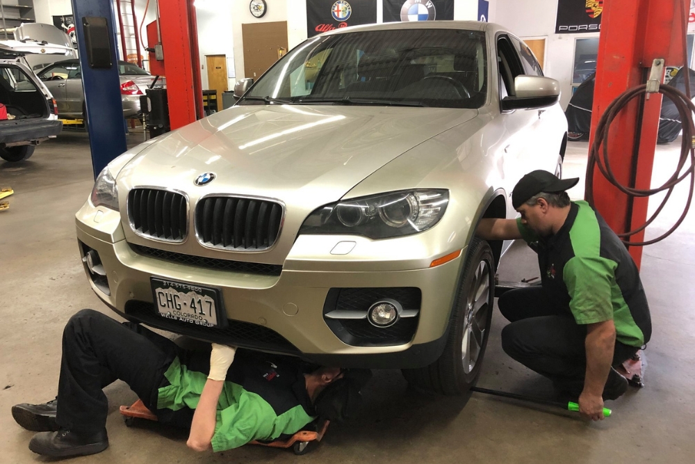 Maintaining Your German Car: Essential Services You Can’t Ignore in Englewood, CO, with Autoimports of Denver. Image of two mechanics checking the underside of the BMW car.