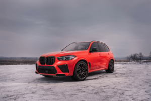 bmw x5 winter maintenance, bmw auto repair, auto repair, Englewood, CO, AutoImports of Denver. Bright orange BMW X5 parked on a snowy landscape, highlighting winter readiness.